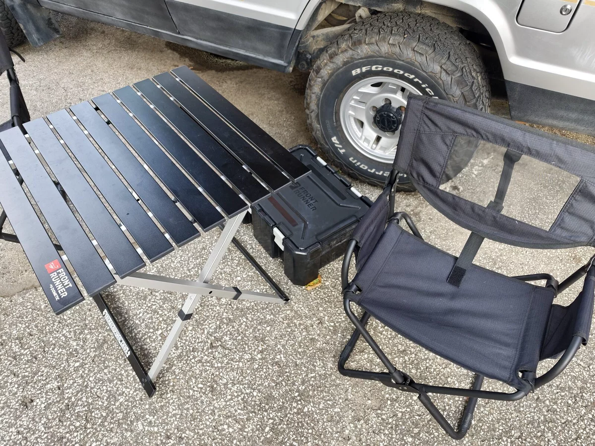 Front Runner folding table and chairs next to an off-roader
