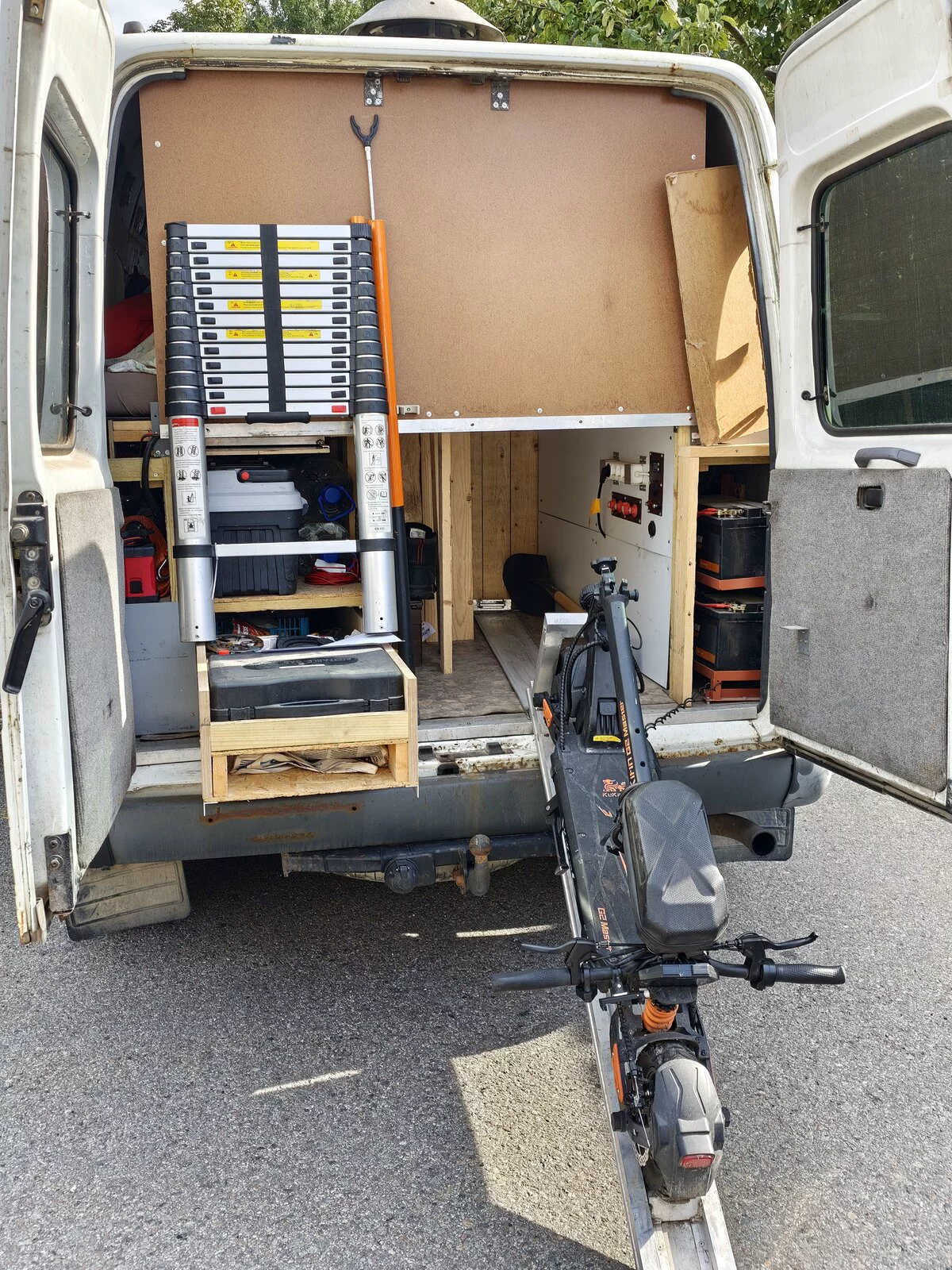 Rear of a workshop-style van: ladder, tool boxes, e-scooter